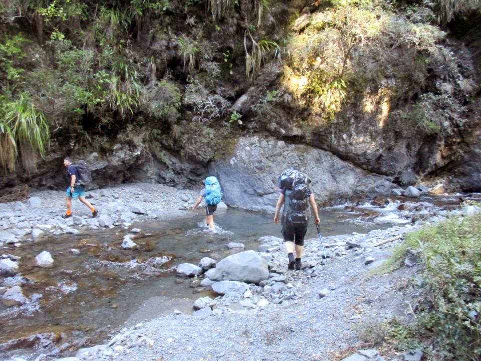 Trampers walk across a river in the Ruahine Ranges