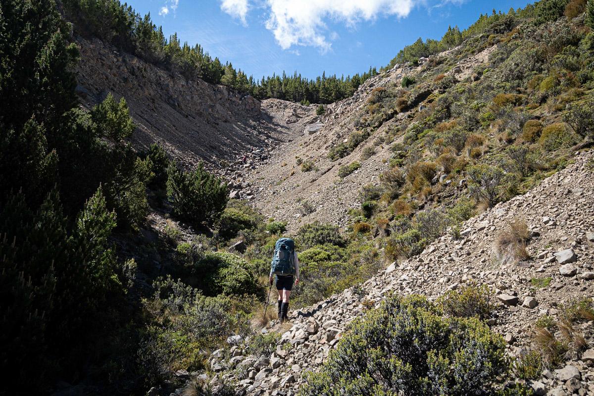 A tramper walks up a scree-filled valley