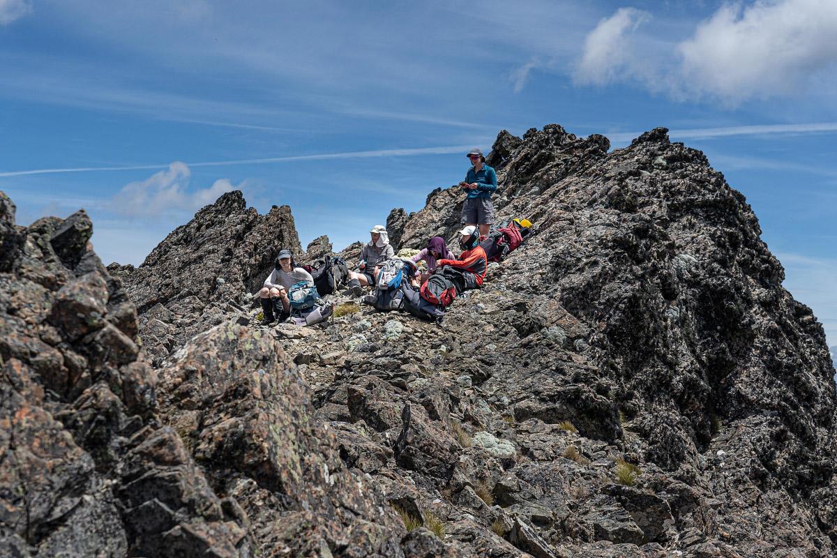 Five trampers resting on a rocky ridgeline