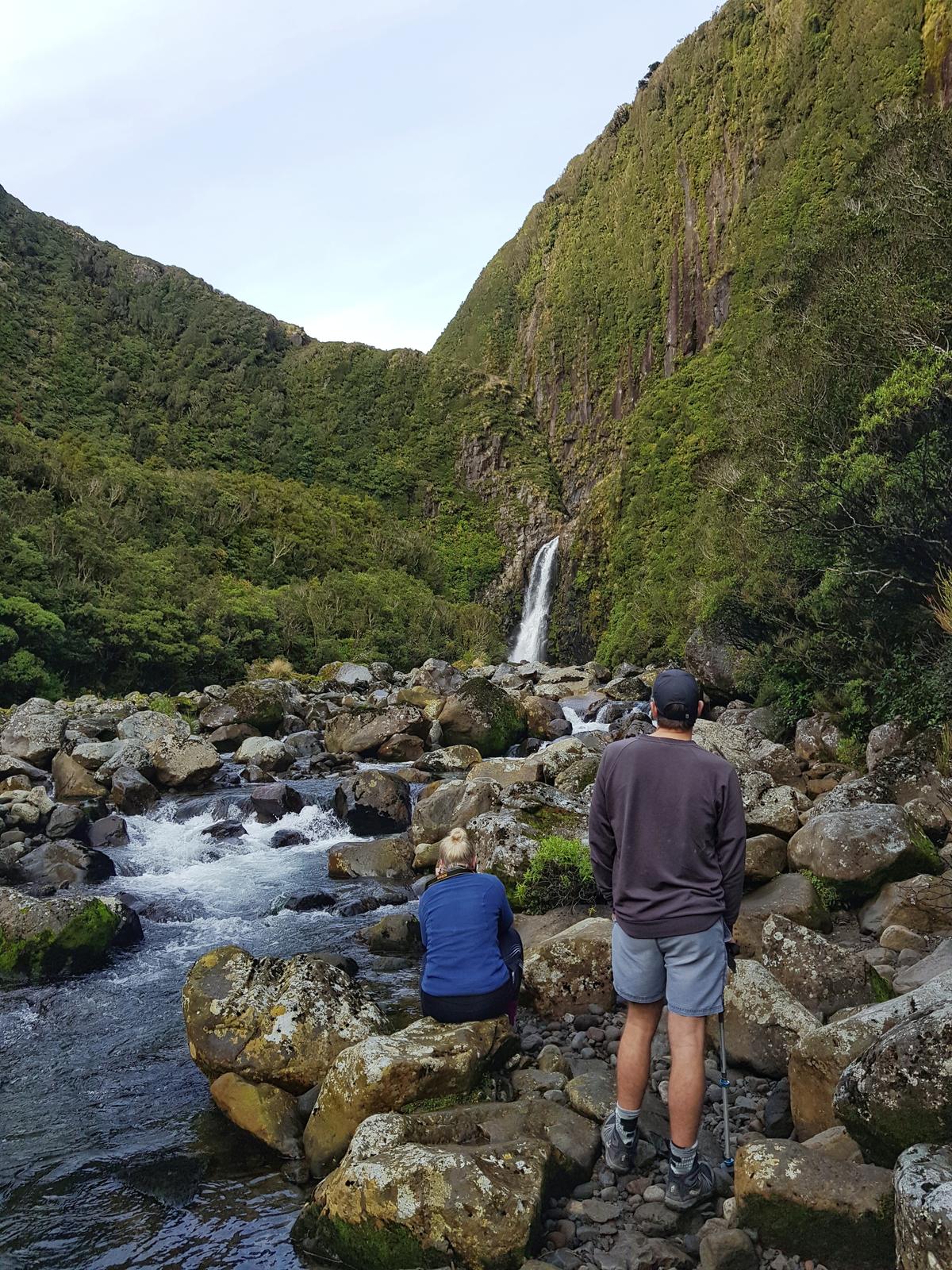 Two trampers looking at a small waterfall