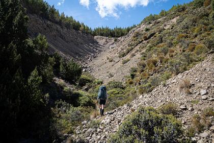 A tramper walks up a scree-filled valley