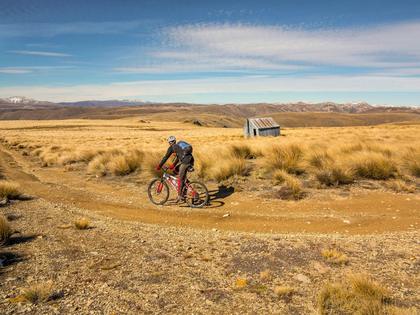 Mountain biking past an old musterers' hut, Hawkdun Range, Otago