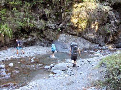 Trampers walk across a river in the Ruahine Ranges