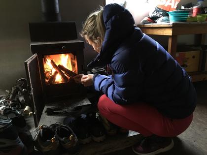 Woman lighting a fire inside a hut