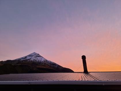 Sunset over hut roof with Taranaki