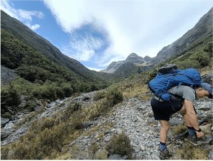 Ellis tying shoe lace with view up valley towards Blue Lake [credit: Josh)