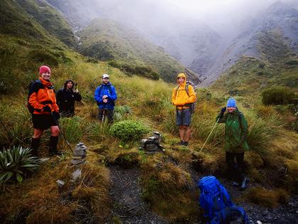 Five very wet-looking trampers under cloud
