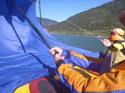 Kayakers improvising a sail from a tarpaulin