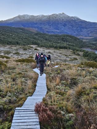 Team ascending boardwalks up to Whakapapa with Mt Ruapehu in background