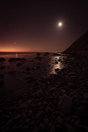 Venus and the Moon reflecting in the calm coastal waters
