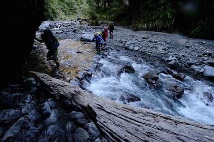 Trampers crossing a river between Black Ridge and Daphne Hut
