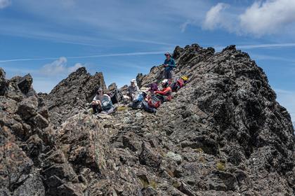 Five trampers resting on a rocky ridgeline