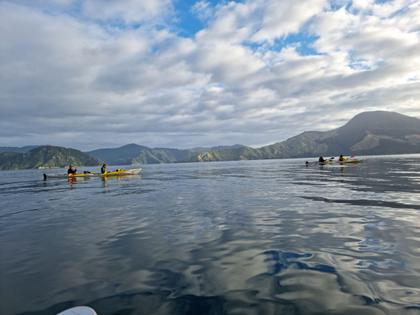 Two kayaks paddling across a backdrop of mountains