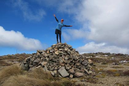 Leader Sarah finds some sunshine on the cairn pile at Kaweka J. Photo credit: Aimee.