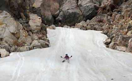 Enjoying a bum-slide down a short snow slope in Mt Taranaki crater.